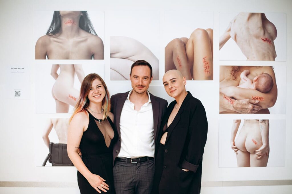 Three people standing in front of pictures