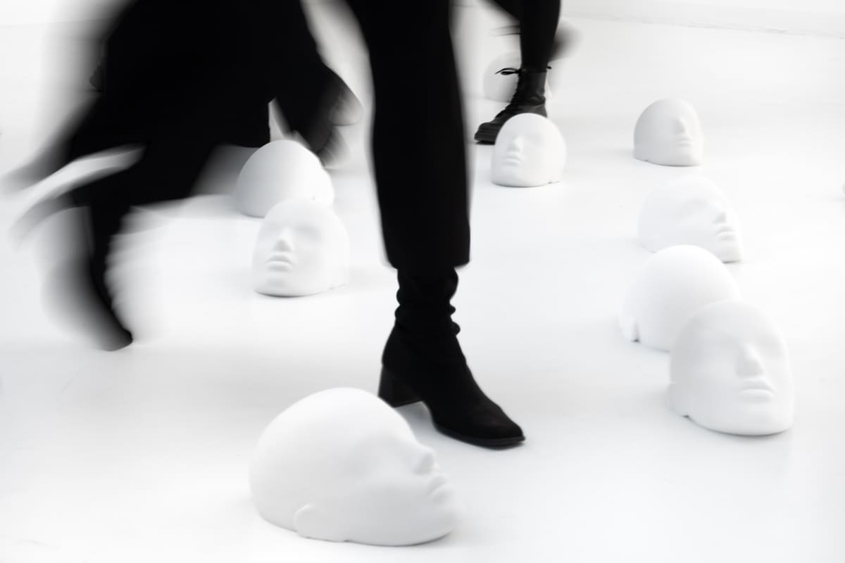 View on sculptures spread around the room laying on the floor with people stepping over it from the project "Femicide" of the Visual Artist Irena Pejčić.