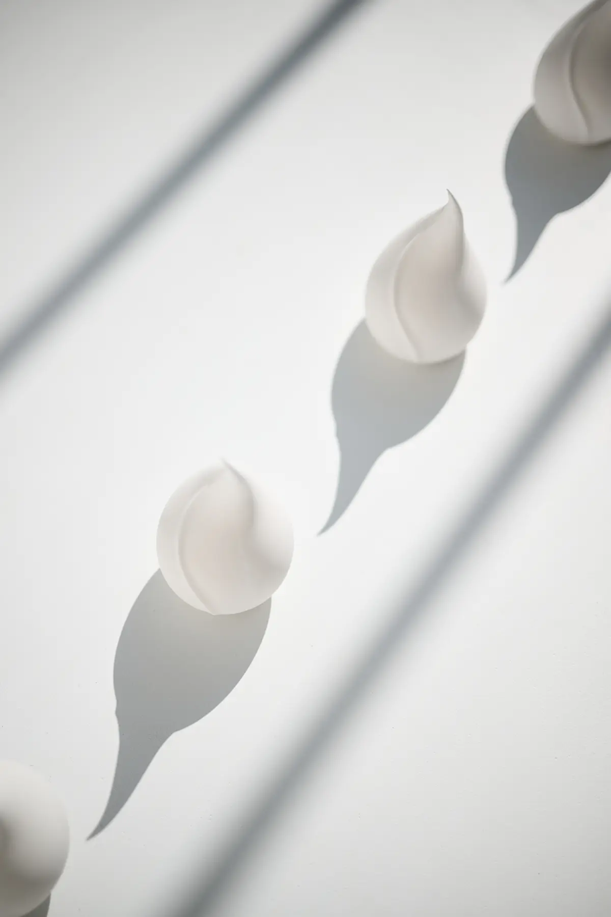 White sculptures shaped like a drop or flame